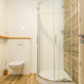 Detail jedné z koupelen Penzionu Kůlna. Dlažbu ve vzhledu dřeva Atom Wood efektně doplňují bílé lesklé obklady White Glossy